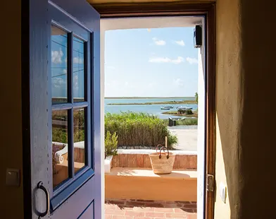 open doorway with coastal lagoon view, terrace entrance with blue door and seaside landscape beyond